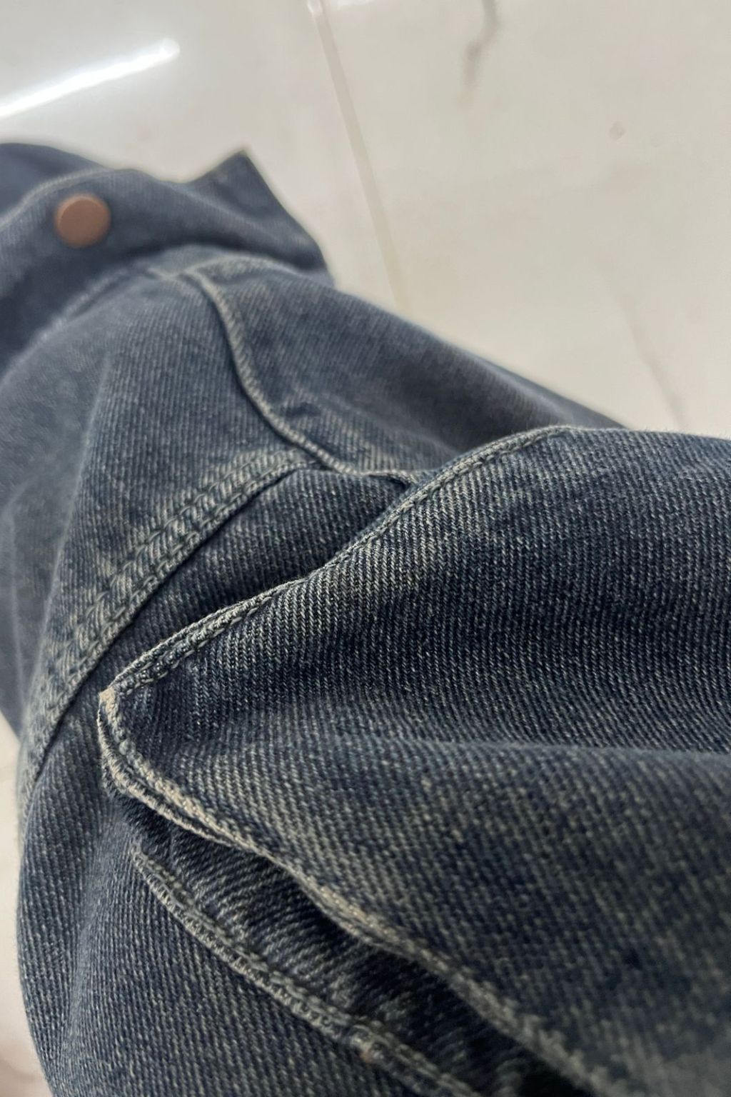 Close-up of blue denim fabric with a button on a white background