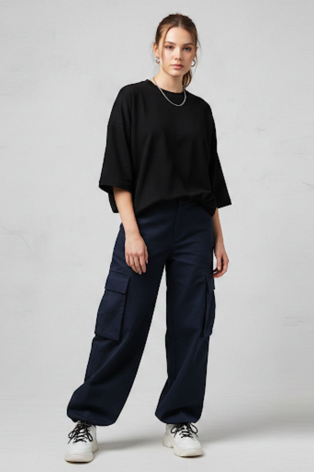Person wearing a black oversized top and navy cargo pants on a light gray background