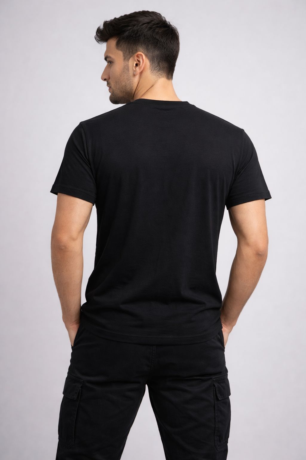 Man wearing a black t-shirt and pants on a light gray background