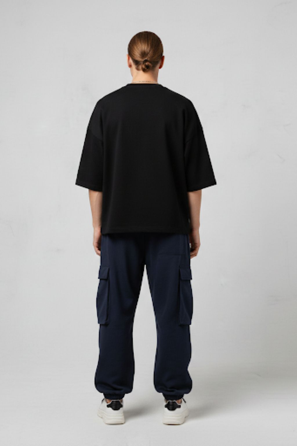 Person wearing a black t-shirt and navy cargo pants on a white background