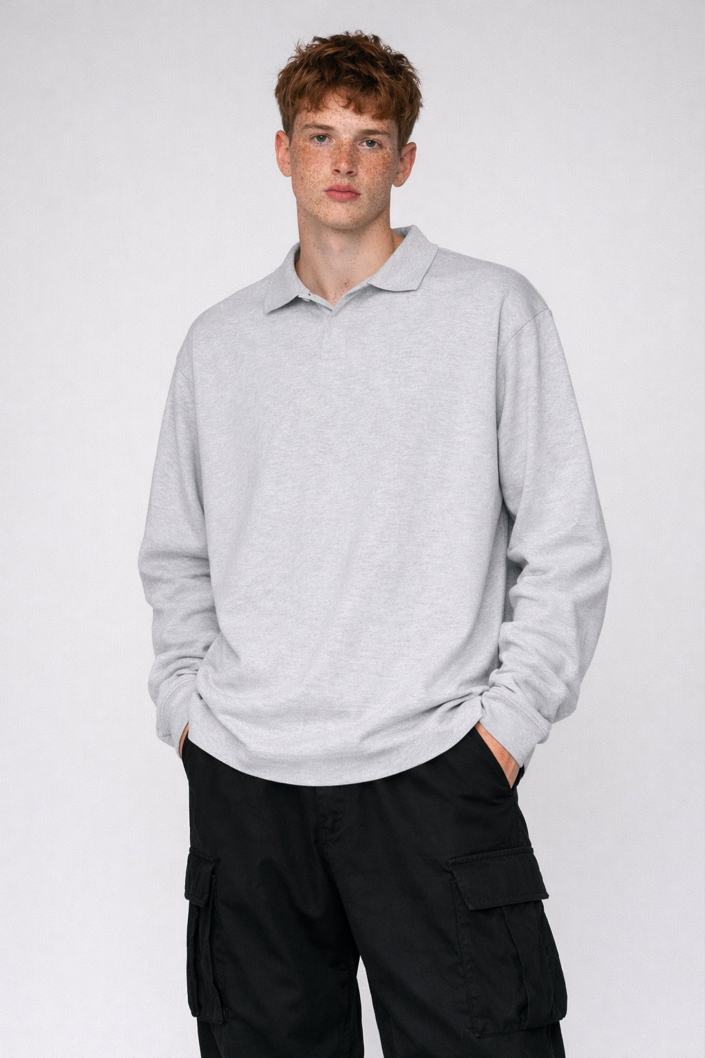 Man wearing a light gray sweater and black cargo pants on a white background